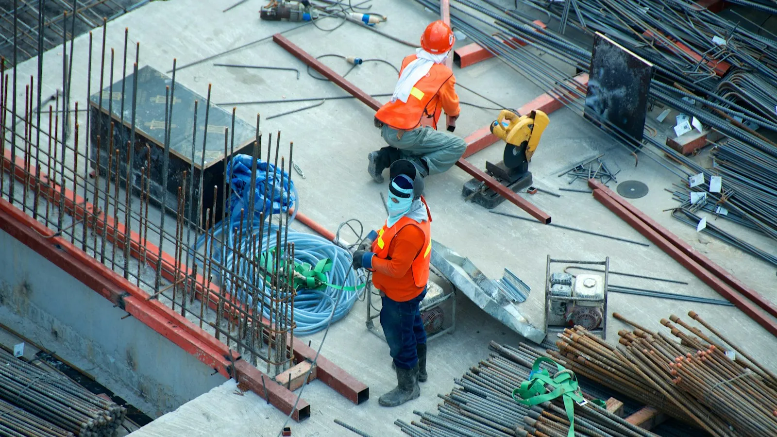 Handwerker mit Schutzhelm und Warnweste auf einer Großbaustelle mit Stahlbewehrung